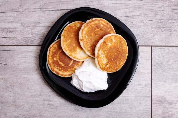 Pannenkoeken en zure room op plaat op houten tafel