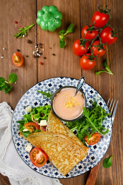 Pannenkoeken gevuld met salami, tomaten, sla, mozzarella en kaassaus.