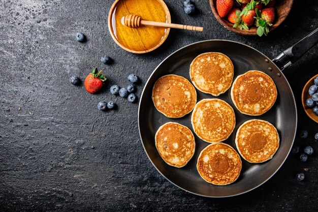 Pannenkoeken in een koekenpan met verse bessen en honing