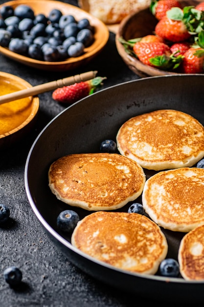 Pannenkoeken in een koekenpan met verse bessen en honing