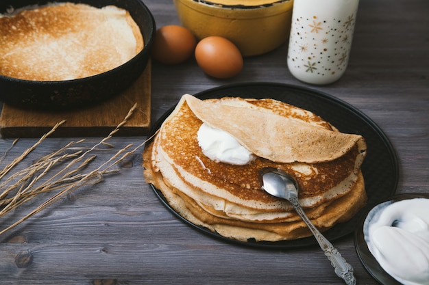 Pannenkoeken in een koekepan en ingrediënten voor hen op een houten tafel