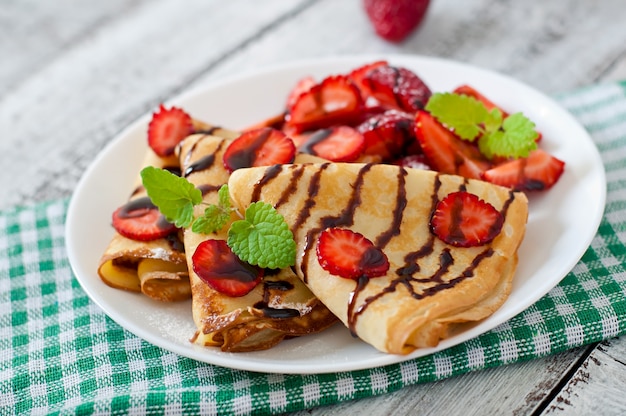 Pannenkoeken met aardbeien en chocolade versierd met muntblad