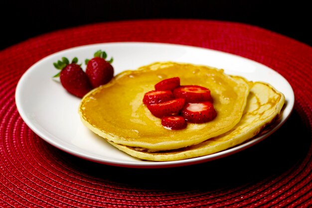 Foto pannenkoeken met aardbeien en stroop in de top