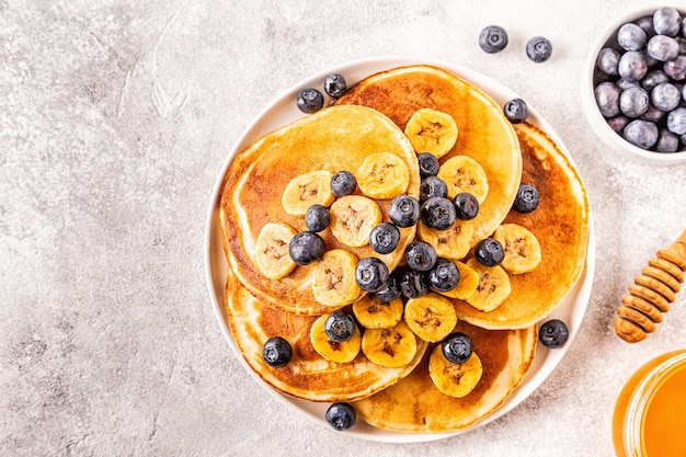 Pannenkoeken met banaan, bosbessen op witte plaat, selectieve aandacht.