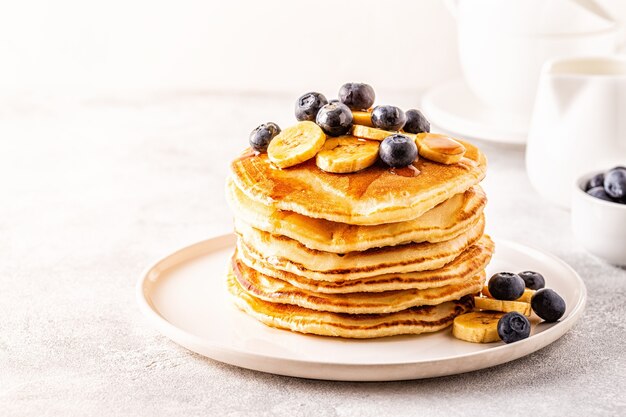 Pannenkoeken met banaan, bosbessen op witte plaat, selectieve aandacht.