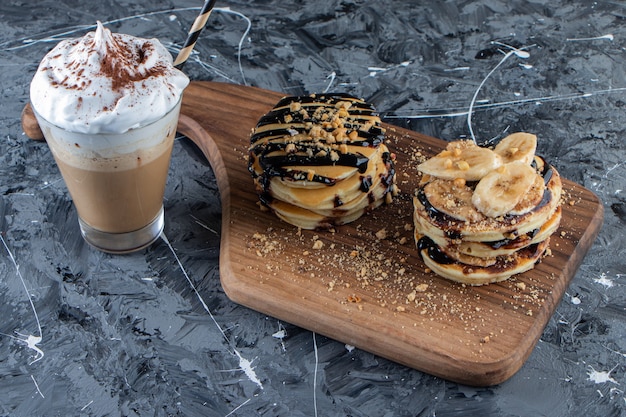 Pannenkoeken met banaan en chocolade topping op een houten bord met heerlijke koffie.