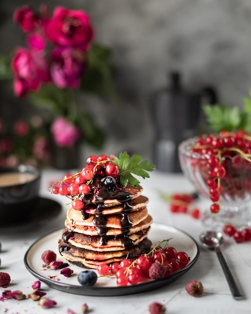 Pannenkoeken met bessen en chocolade met een boeket rode rozen.