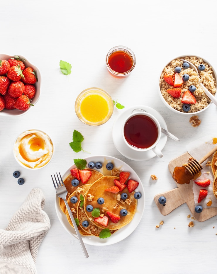 Foto pannenkoeken met bosbessen aardbeien honing en quinoa voor het ontbijt