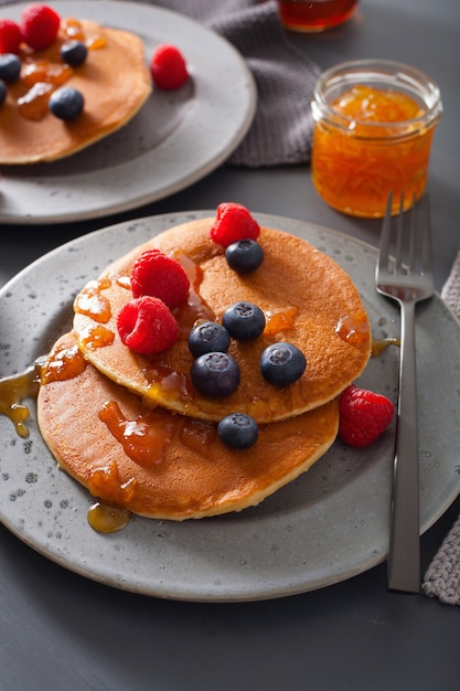 Pannenkoeken met bosbessen frambozen honing en jam voor het ontbijt