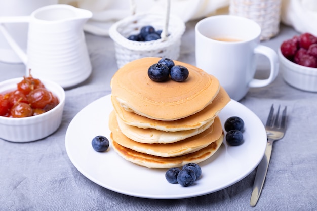 Pannenkoeken met bosbessen, kersen en mini-appeljam. Een kopje koffie en juskom op de achtergrond. Traditionele Amerikaanse Pannenkoeken. Detailopname.