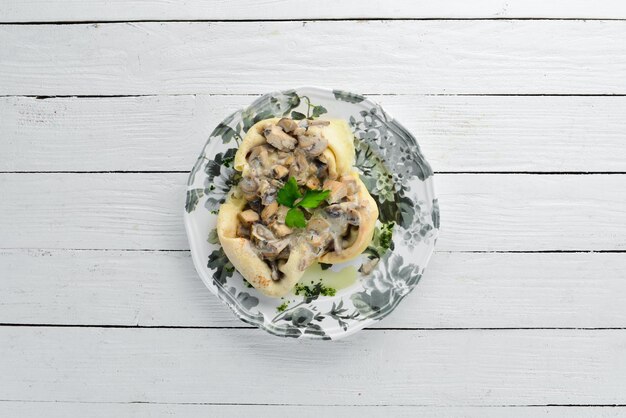 Pannenkoeken met champignons, kaas en roomsaus Op een houten ondergrond Bovenaanzicht Vrije ruimte voor uw tekst