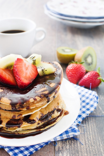 Pannenkoeken met chocolade, aardbeien en kiwi op houten tafel