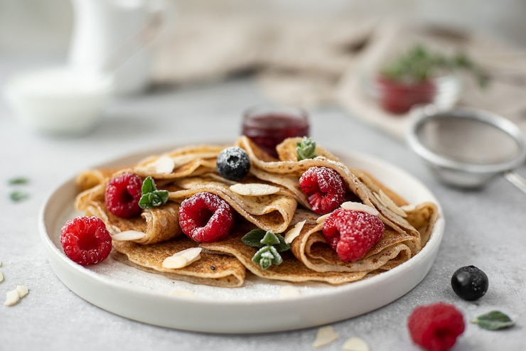 Foto pannenkoeken met jam en verse bessen, bestrooid met poedersuiker, close-up