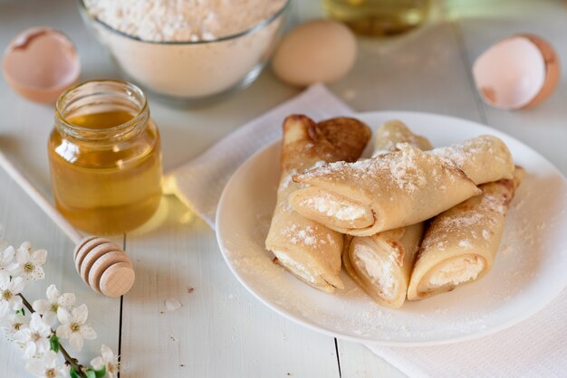 Pannenkoeken met kwark op een witte houten achtergrond. shot met honing, zonnebloempitten, meel en eieren. een traditioneel ontbijt.