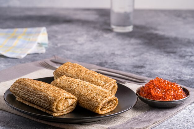 Pannenkoeken met rode kaviaar op zwarte plaat. Russische keuken. Maslenitsa.