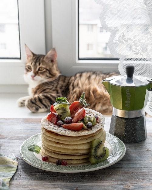 Pannenkoeken met verse bessen van frambozen, krenten, bosbessen, met honing en thee