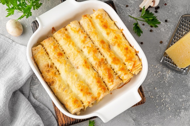 Pannenkoeken of dunne pannenkoeken gevuld met kip en champignons gebakken met kaas in een ovenschaal