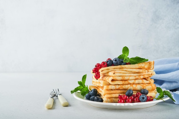 Pannenkoeken Stapel pannenkoeken of dunne pannenkoeken met bessen bosbessen rode aalbessen frambozen en honing voor het ontbijt Zelfgemaakt ontbijt Kopieer ruimte Selectieve aandacht