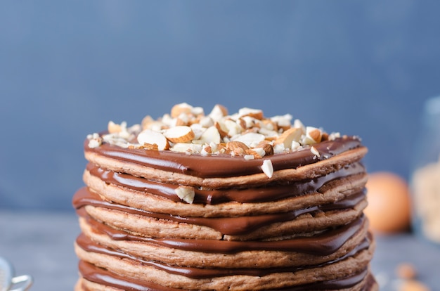 Pannenkoeken taart. Een stapel van chocoladepannekoeken met chocoladeroom en amandelen bovenop.