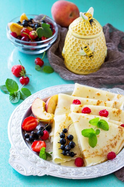 Pannenkoekenontbijt met honing en verse bessen van krenten aardbeien nectarines