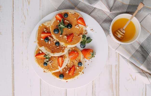 Pannenkoekenontbijtconcept met honing en notenbessen.