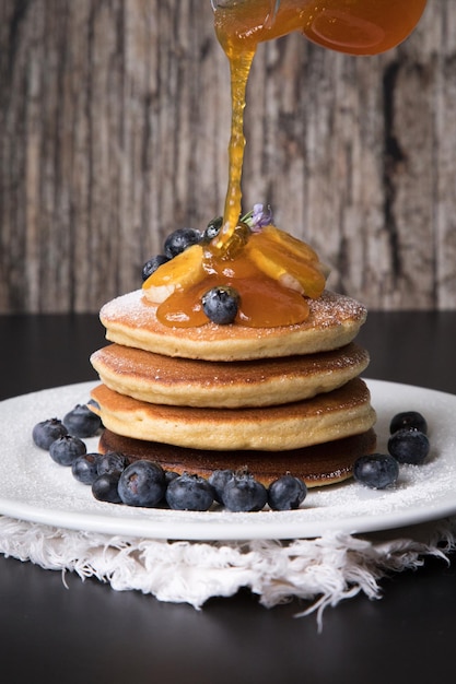 Pannenkoekenstapel met topping van banaan en bosbessen en bijenhoningontbijt