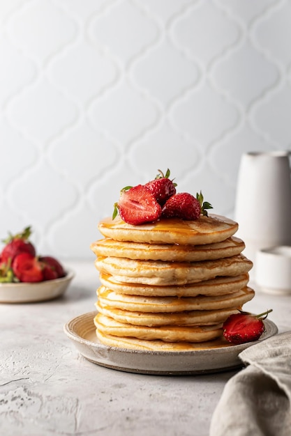 Pannenkoekenstapel met verse aardbeien bij witte tegelachtergrondontbijtsamenstelling