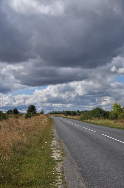 人けのない道に沿ったパノラマ。雨が降る前の道路の眺め。空の雲。