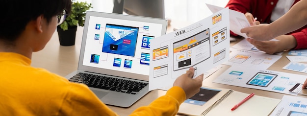 Panorama banner of startup ux developer or company employee design user interface or ui prototype for mobile application or website software with software display on laptop monitor in office synergic