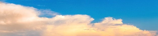 Panorama of blue sky with light fluffy clouds at sunset