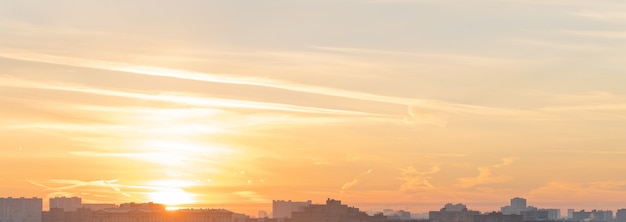 A panorama of a bright golden sunrise or sunset over the rooftops of a big city