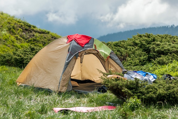 Panorama of cold foggy summer morning and tourist hikers tent in Carpathian mountains