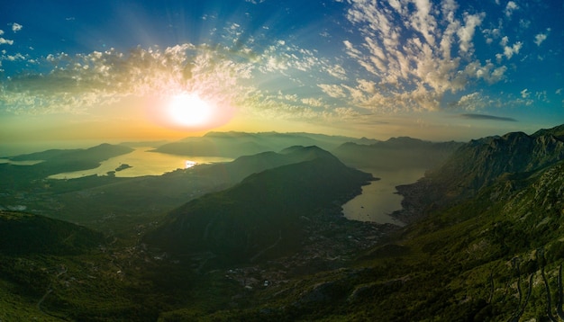 Panorama of dazzling sun in the evening sky illuminates all the peaks of the balkan montenegrin moun