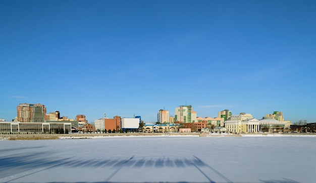 Panorama of a frozen river and buildings illuminated by the sun on a winter day