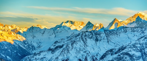 Panorama of high mountains peaks at sunset. Landscape on snow hills