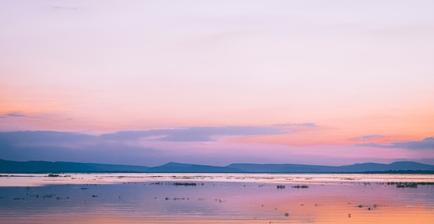 ピンクの空と夕暮れ時のパノラマの湖と山の風景