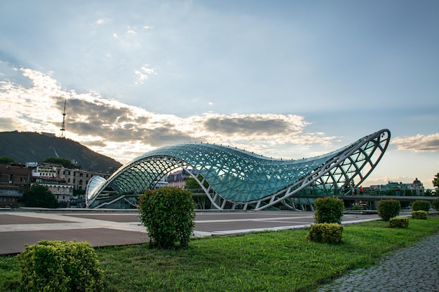 A panorama landscape with a pedestrian bridge of peace across the Kura River and old town at sunset on a cloudy summer day Tbilisi Georgia