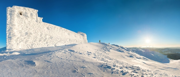 Panorama met man op de top van de winterberg in sneeuw bij zonsondergang