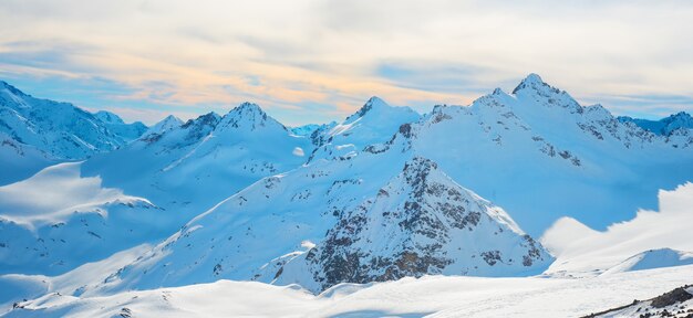 Panorama met waaier van bergtoppen in sneeuw bij zonsondergang