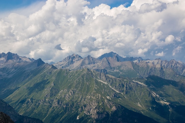 Panorama della scena delle montagne con il cielo nuvoloso drammatico nel parco nazionale di dombay, caucaso, russia. paesaggio estivo e giornata di sole