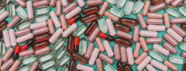 Panorama multicolored pills and capsules on a green background