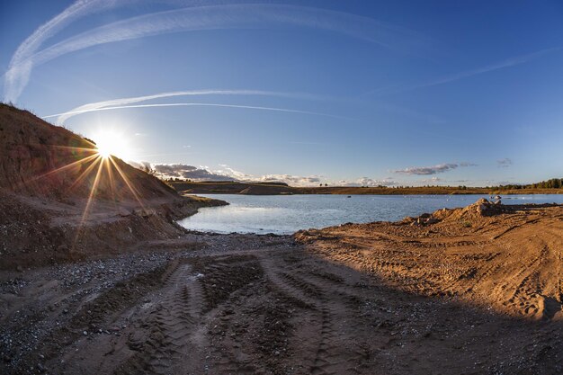 Panorama near quarry flooded with water for sand extraction mining in the evening sun