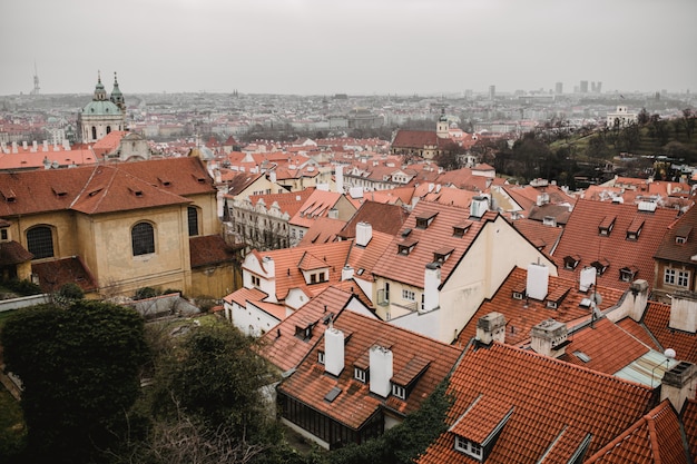 Panorama of Prague with red roofs and Church. City view of Praha old city. Rustic grey colors toning