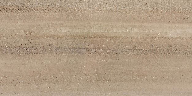 Панорама дороги сверху на поверхности гравийной дороги с следами автомобильных шин в сельской местности