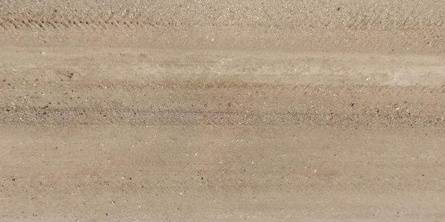 panorama of road from above on surface of gravel road with car tire tracks in countryside