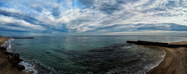 Panorama of the sea coast with stone piers clouds