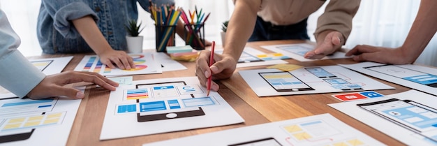 Panorama shot of frontend developer team brainstorming UI and UX designs for mobile app on paper wireframe interface User interface development team planning for userfriendly UI design Scrutinize