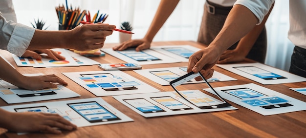 Panorama shot of frontend developer team brainstorming UI and UX designs for mobile app on paper wireframe interface User interface development team planning for userfriendly UI design Scrutinize