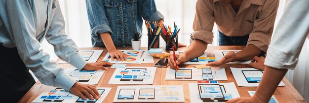 Panorama shot of frontend developer team brainstorming UI and UX designs for mobile app on paper wireframe interface User interface development team planning for userfriendly UI design Scrutinize