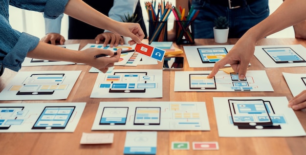 Panorama shot of frontend developer team brainstorming UI and UX designs for mobile app on paper wireframe interface User interface development team planning for userfriendly UI design Scrutinize